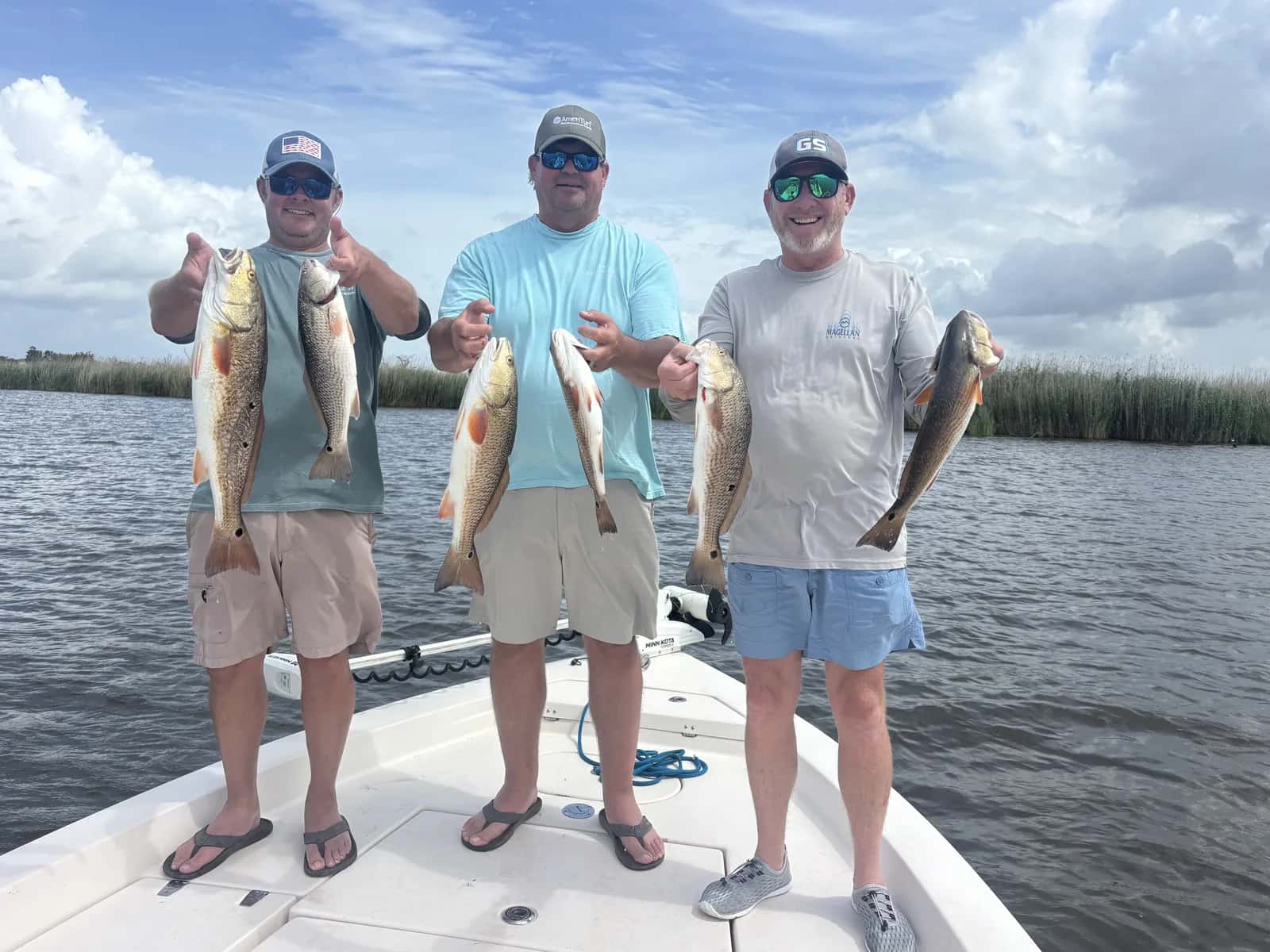 Three anglers displaying their catch aboard a fishing boat
