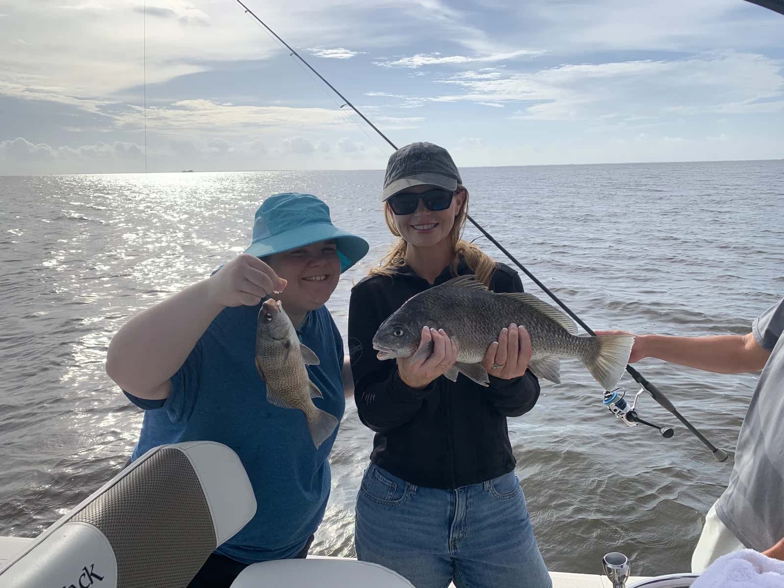 Two anglers holding fish while others fish from the boat