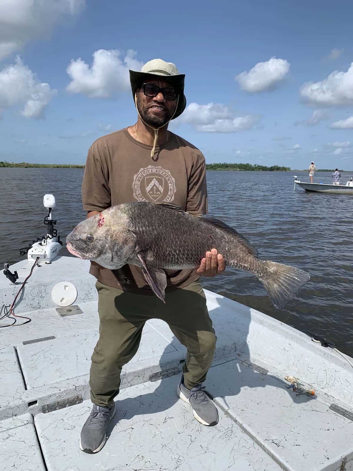 Angler holding a dark-colored fish on the boat