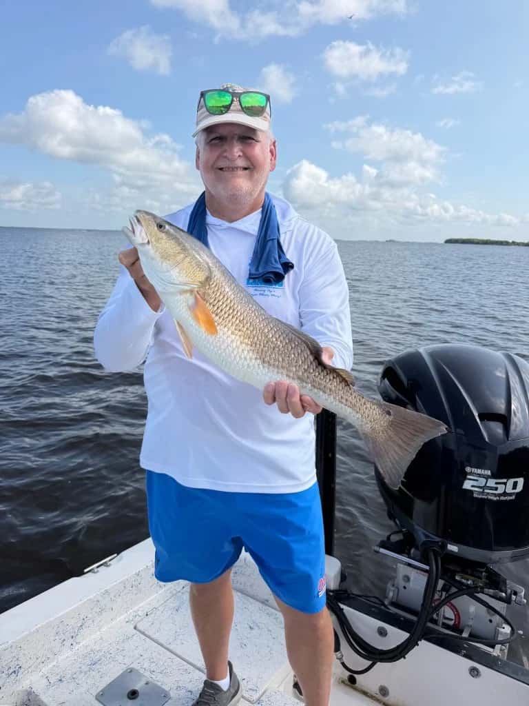 Angler holding a fish beside the boat motor