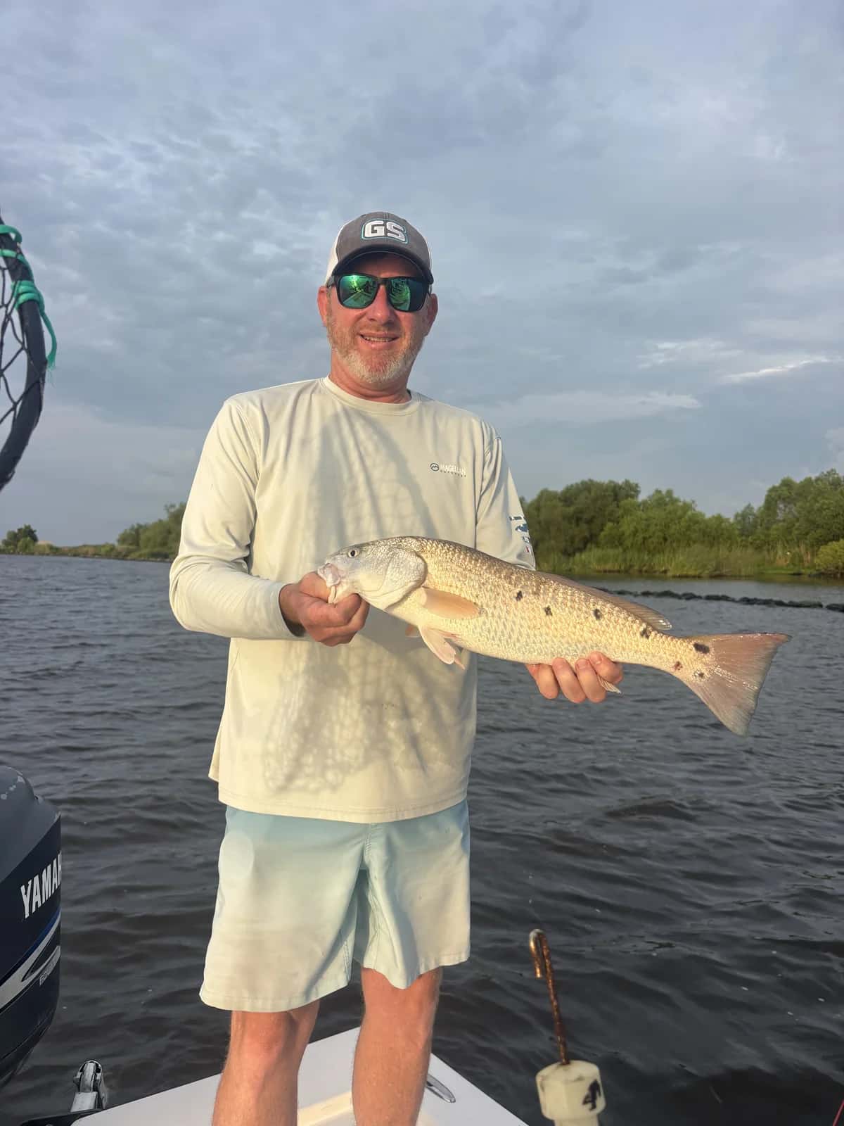 Angler holding a fish beside open coastal water