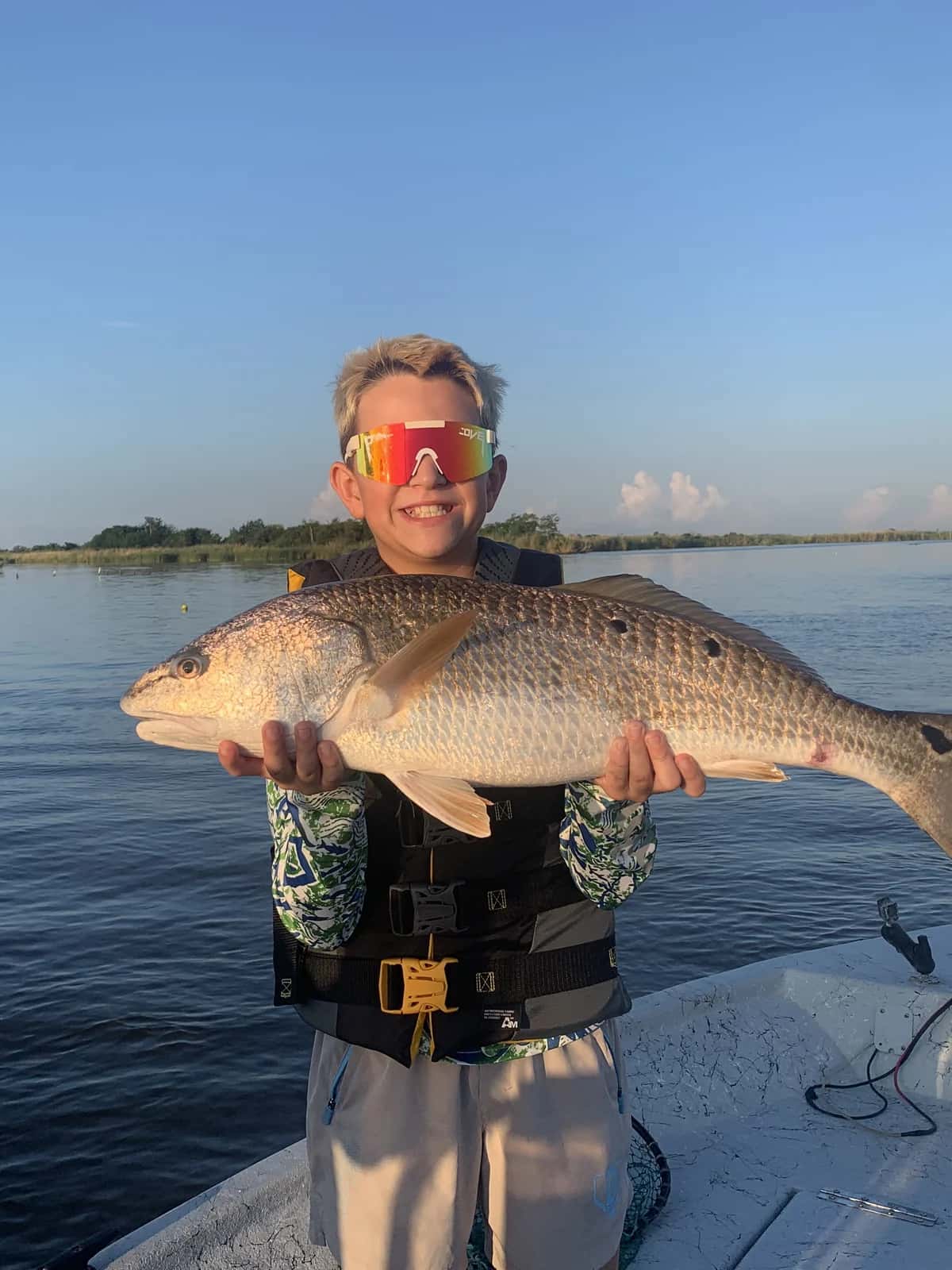 Angler holding a fish with marsh vegetation nearby