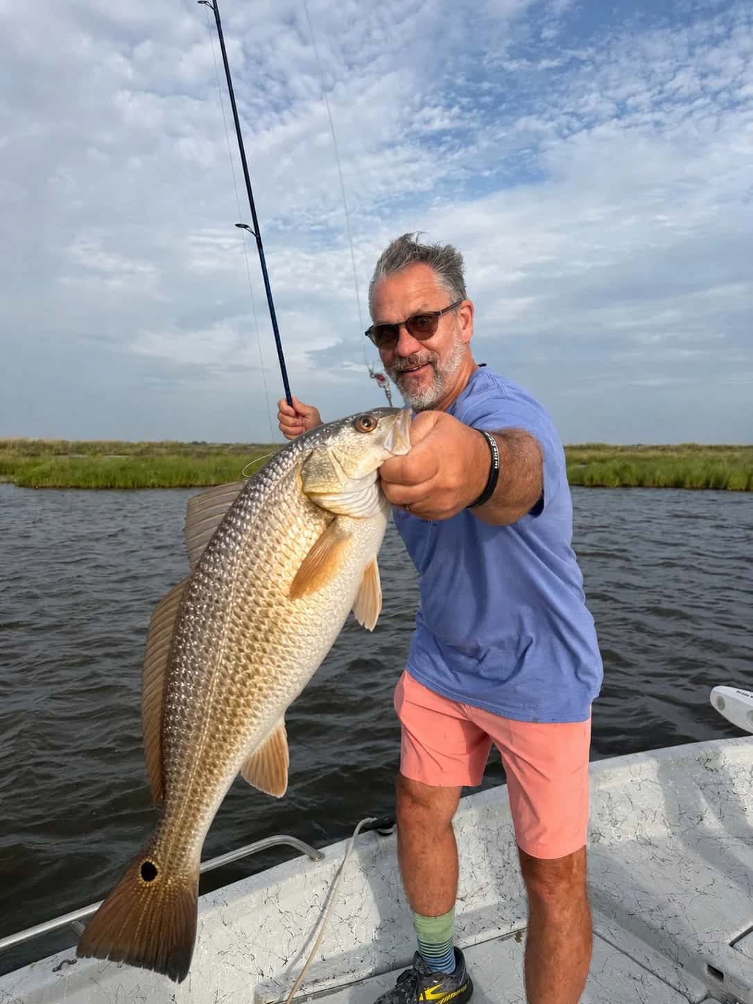 Angler holding a large fish on the deck of a fishing boat