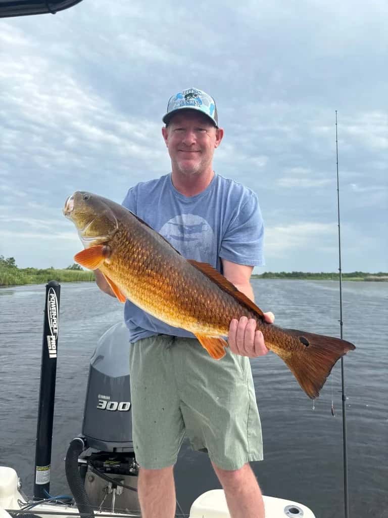 Smiling angler holding a large fish on the boat
