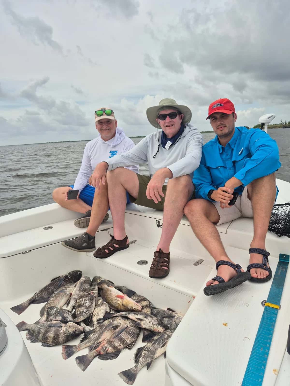 Three anglers seated on a boat with their catch